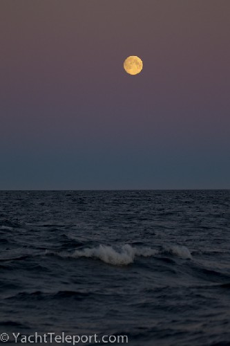the full moon rising above the ocean