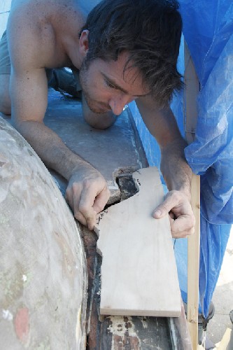 Chris laying in the jigsaw puzzle piece of wood to replace the rotten section